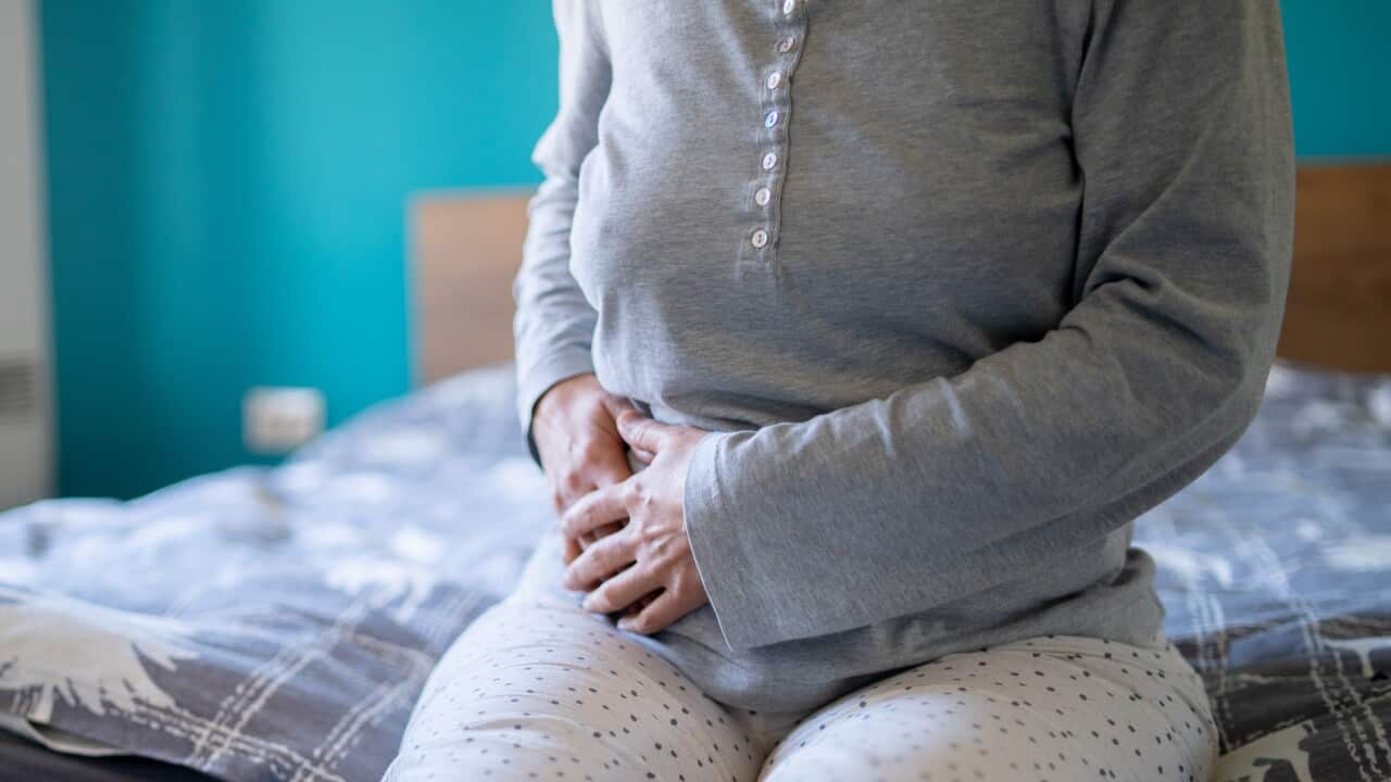 A woman holding the right side of her stomach.