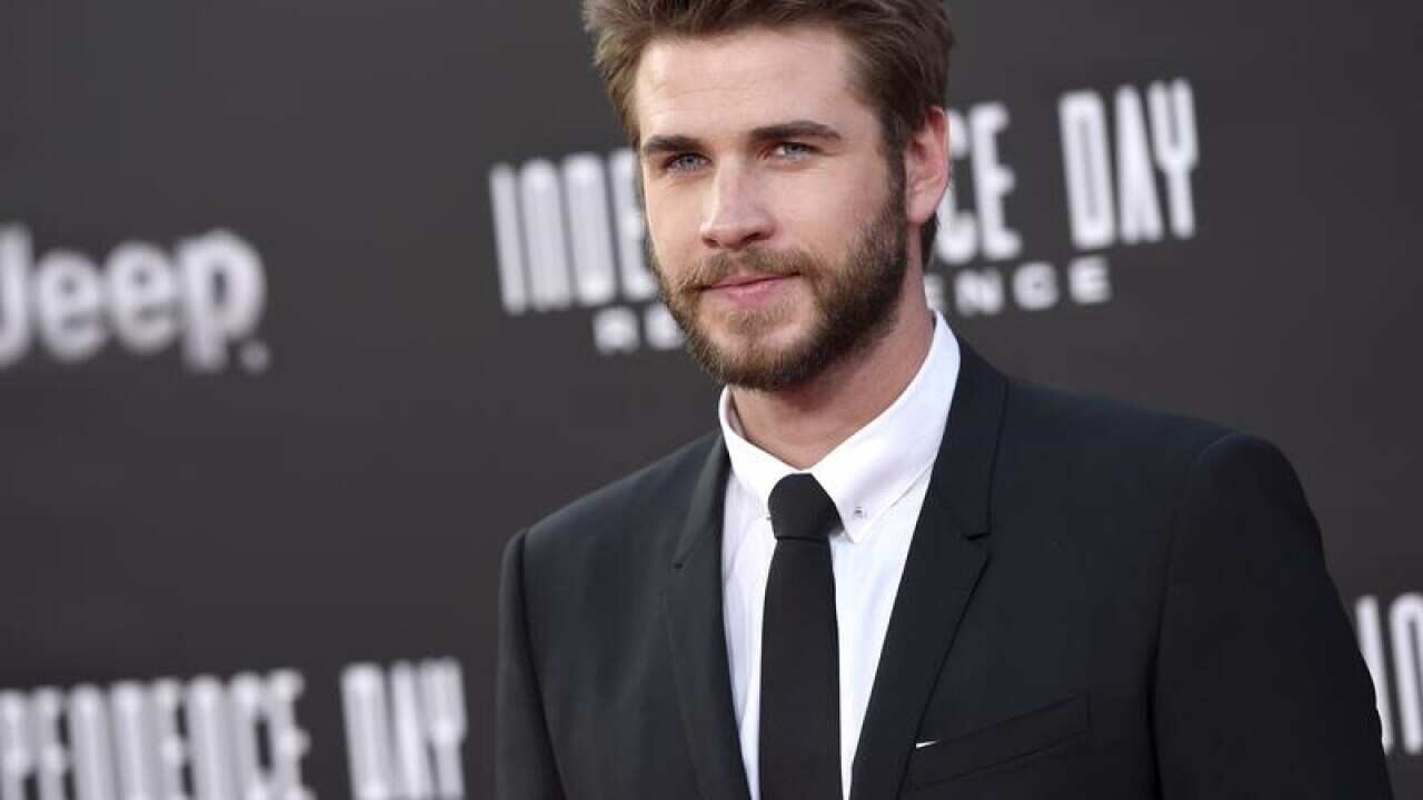 Liam Hemsworth arrives at a movie premiere.