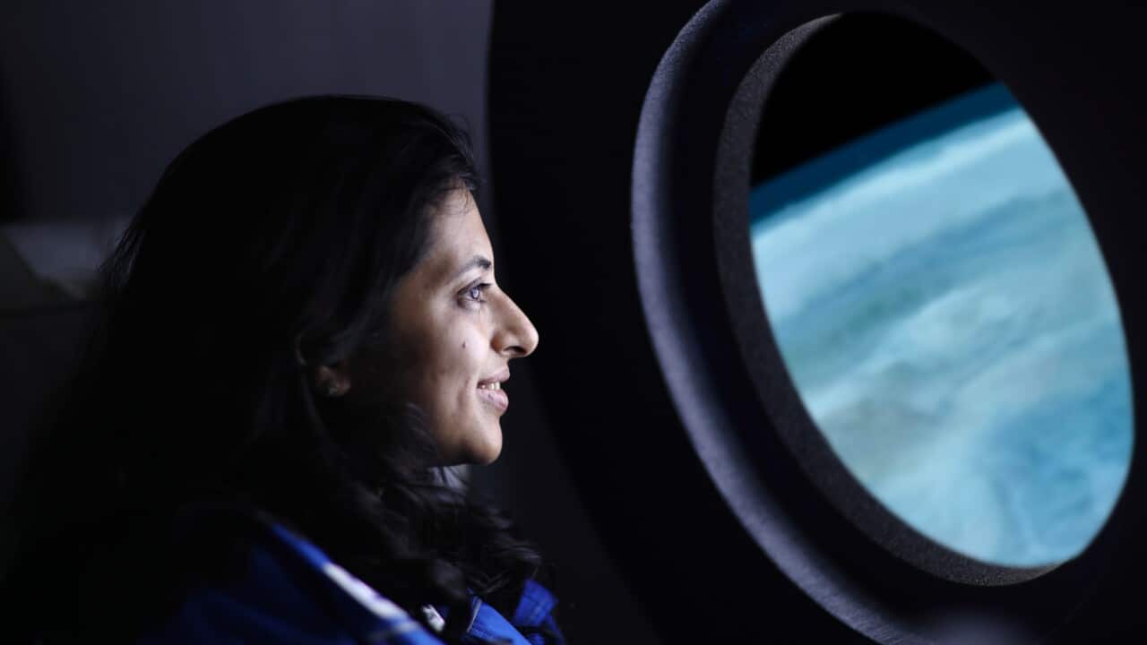 A commercial space traveler looking at the earth through window of the spaceship.