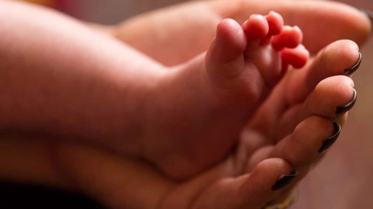 a mother holding the feet of a new baby