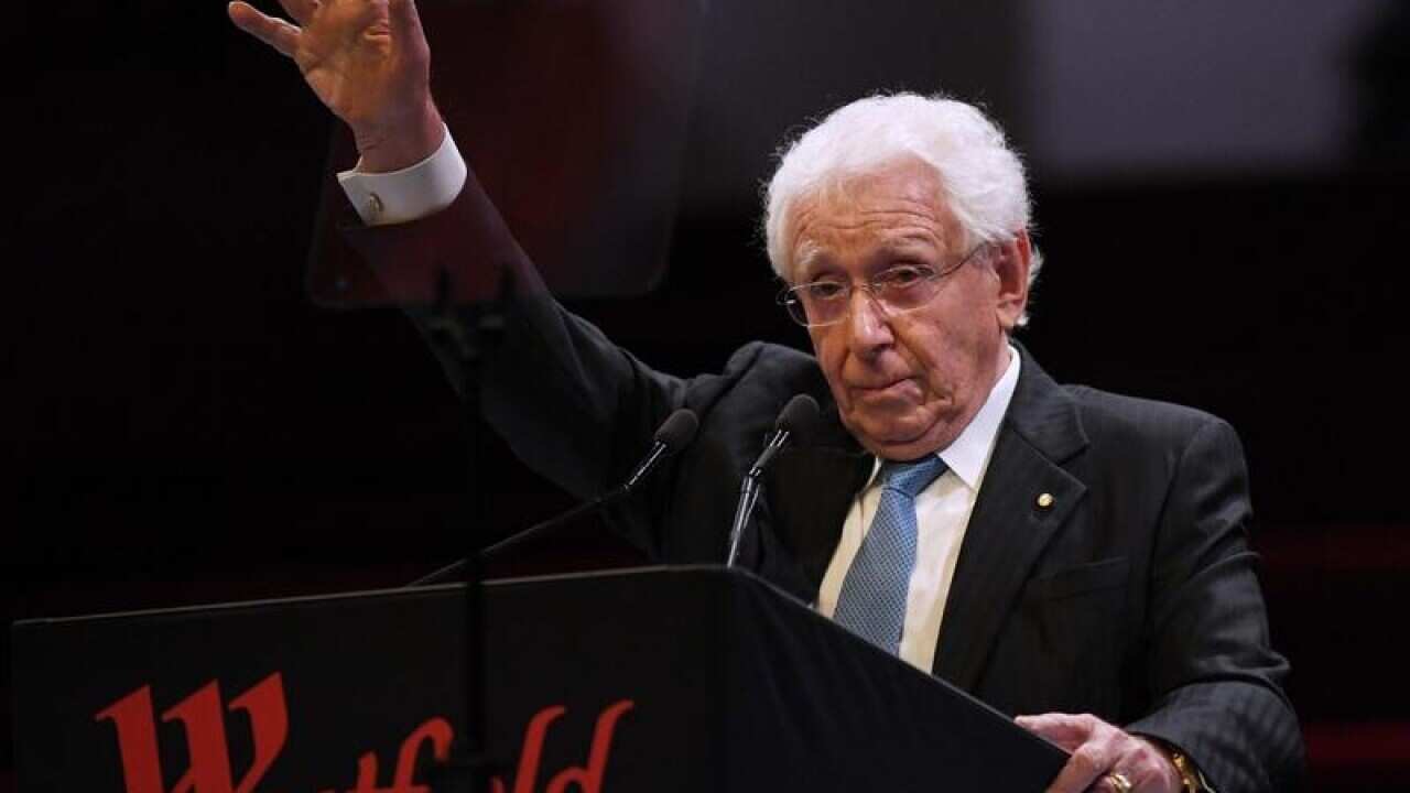Westfield chairman Frank Lowy gestures while standing at a podium.