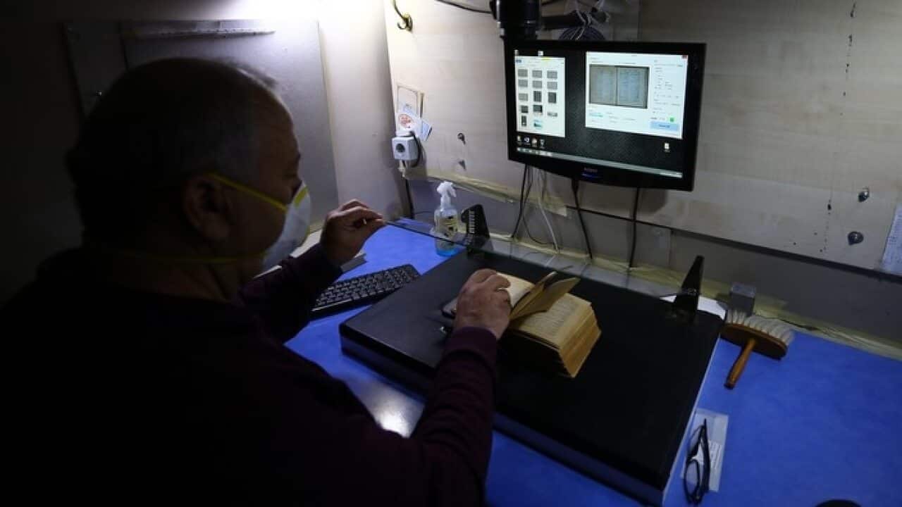A technician transfers precious physical texts into a digital format