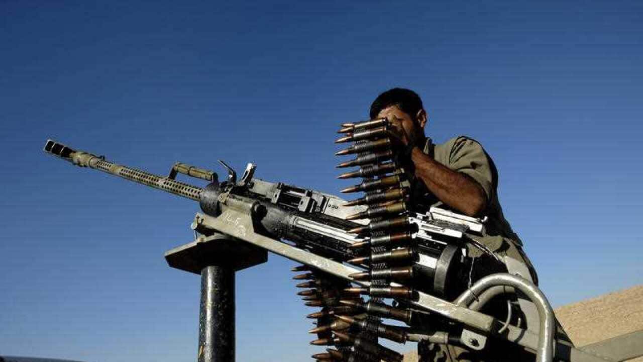 A member of the Kurdistan Workers Party (PKK) inspects his weapon while helping patrol the outskirts of Makhmur, a northern Iraqi town near Erbil