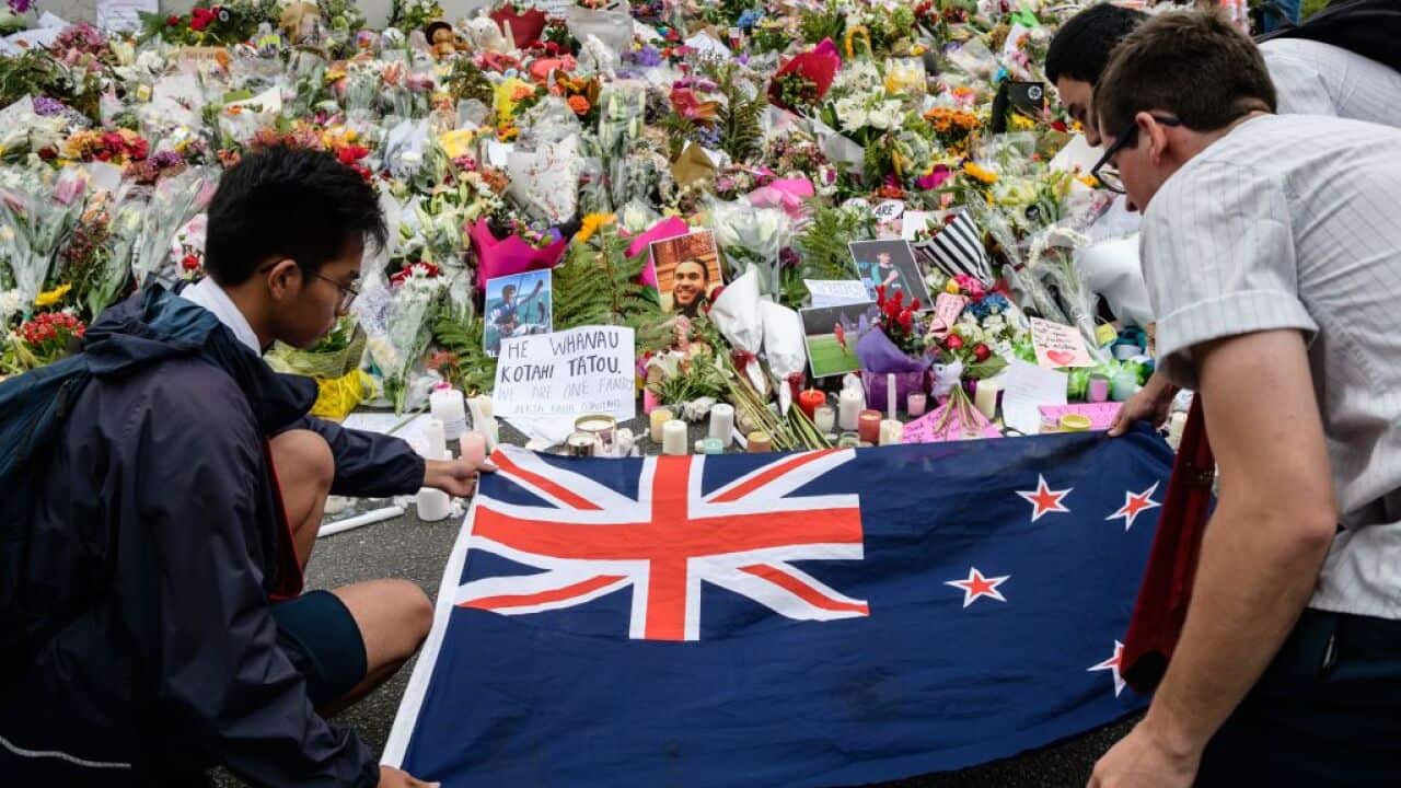 Students display the New Zealand national flag next to flowers