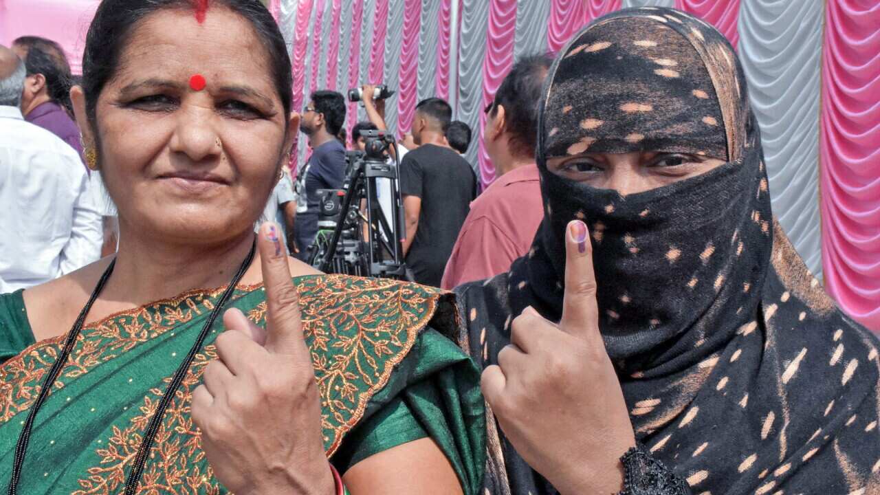 Mumbai: Voters show their ink-marked fingers after casting their vote