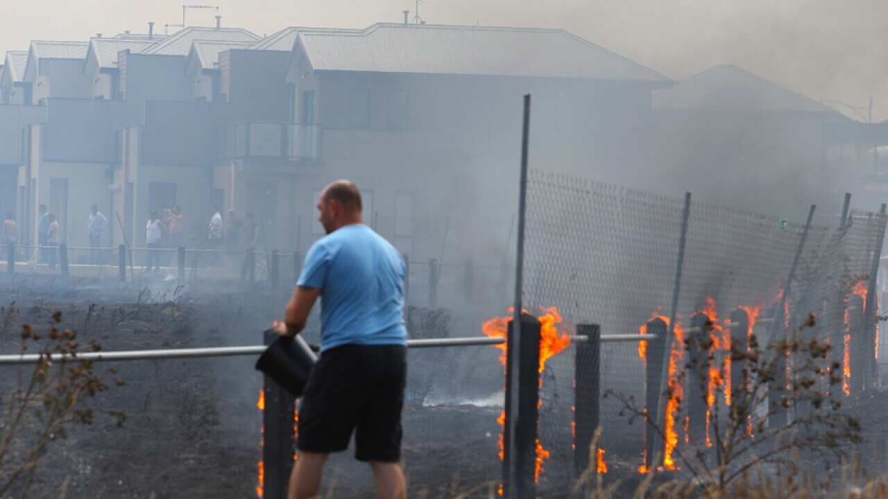 Residents with buckets battle a fast moving grass fire