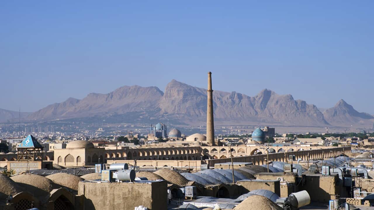 A cityscape of the Iranian city of Isfahan, with buildings and mountains in the distance.