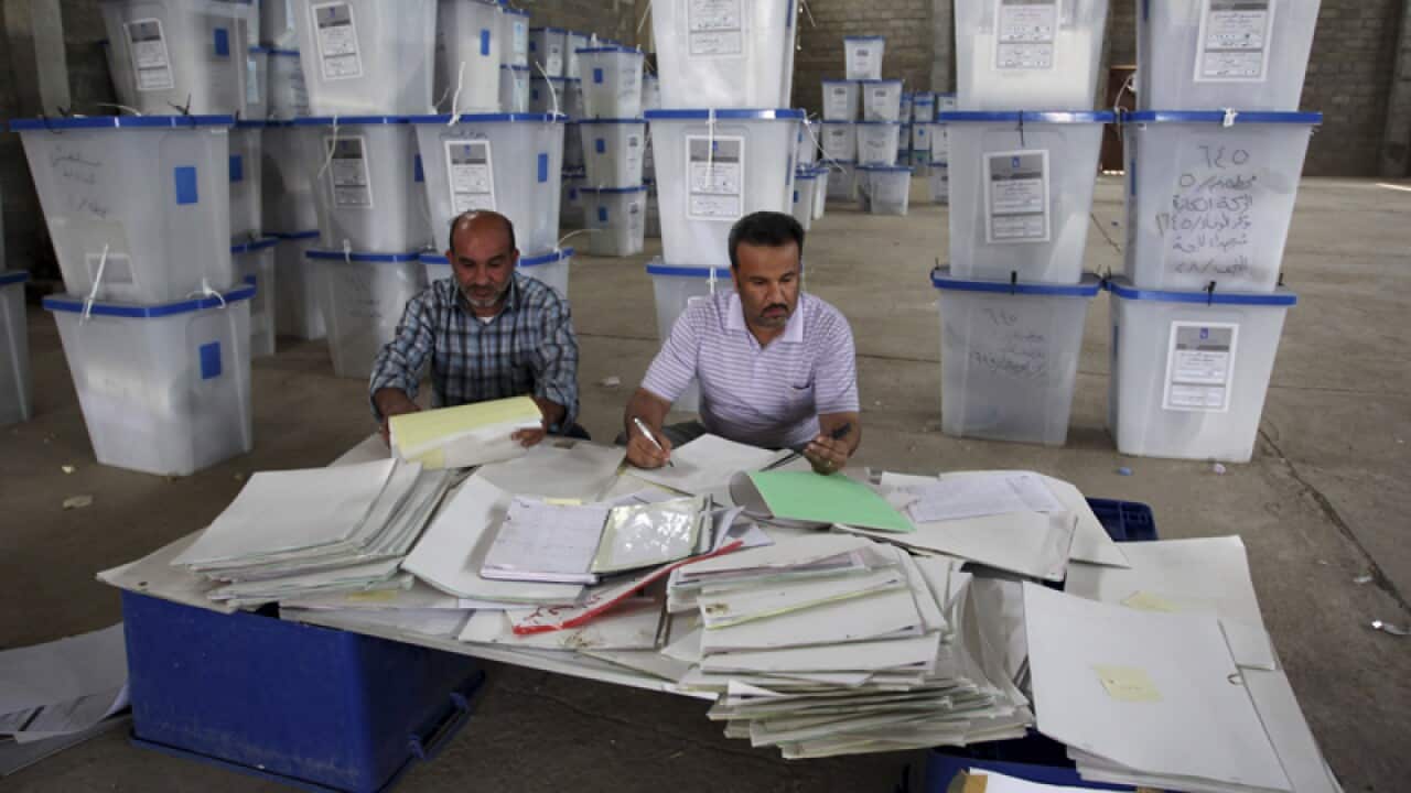 Electoral workers sit amongst piles of ballot boxes