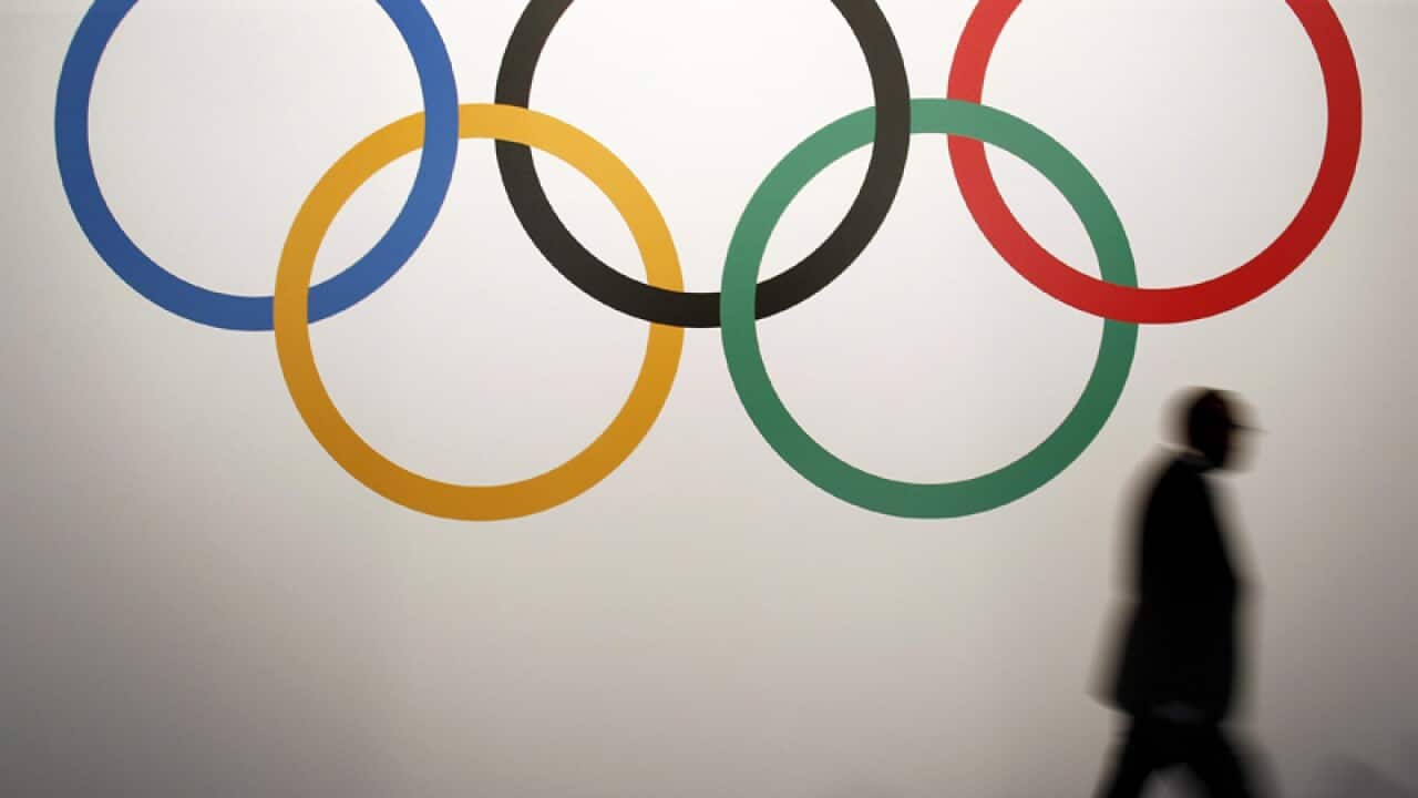 A man walks past the Olympic rings.