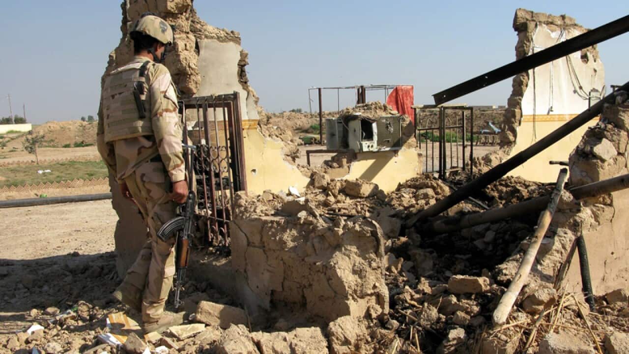 An Iraqi officer looks over damage from fighting in Tikrit