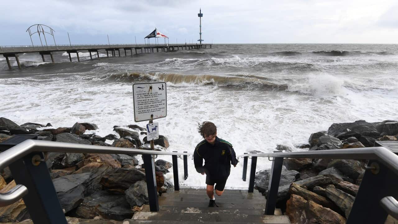 A boy runs up steps to avoid a wave as high tide and a storm surge at Brighton Jetty, Adelaide.
