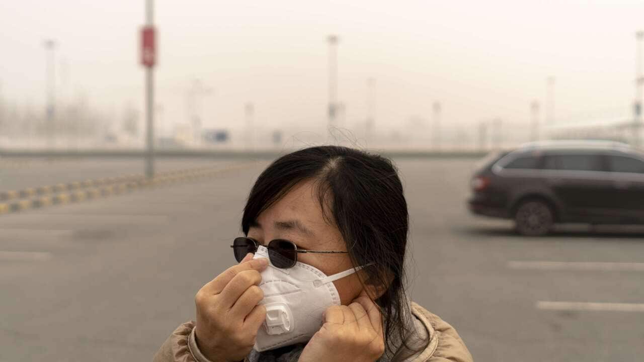 A girl wears mask walking in a parking lot on a heavy hazy day