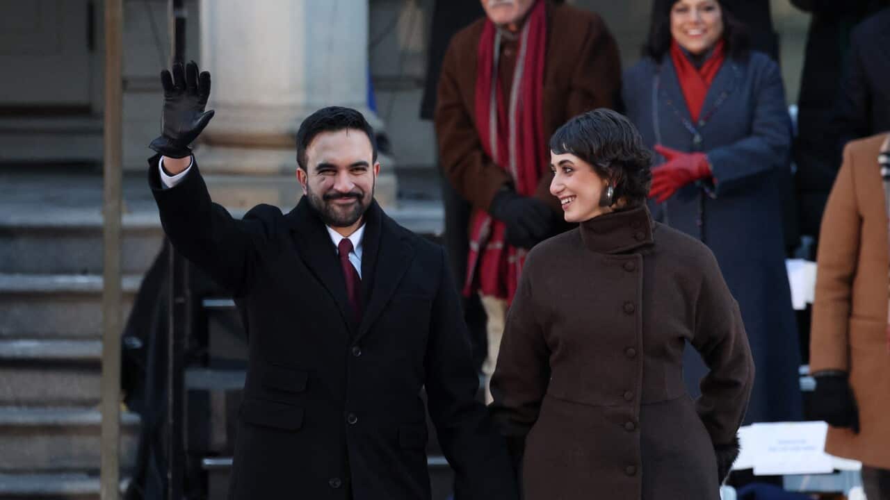 A man waves while holding hands with a woman.