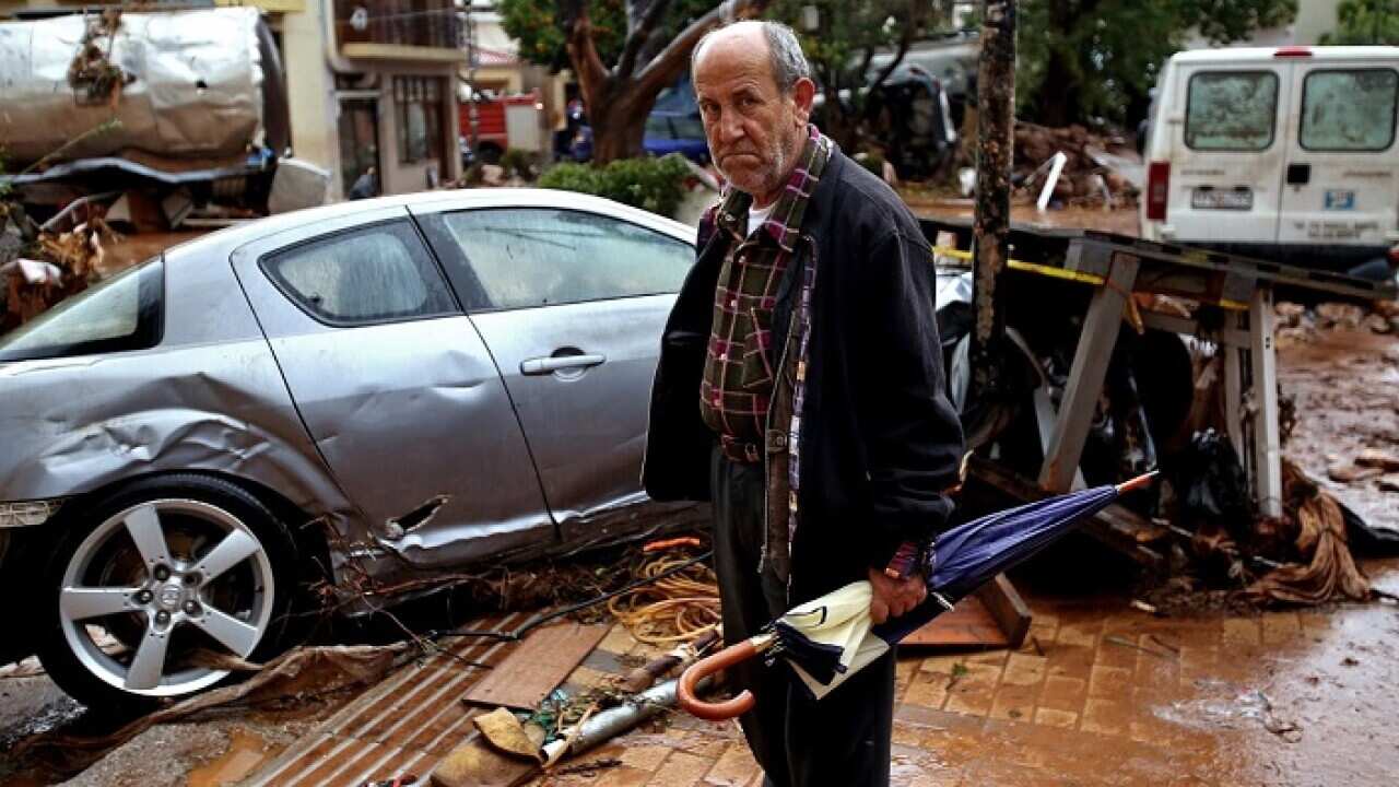 A man stands in front of destroyed cars in the center of Mandra, Western Attica, Greece.