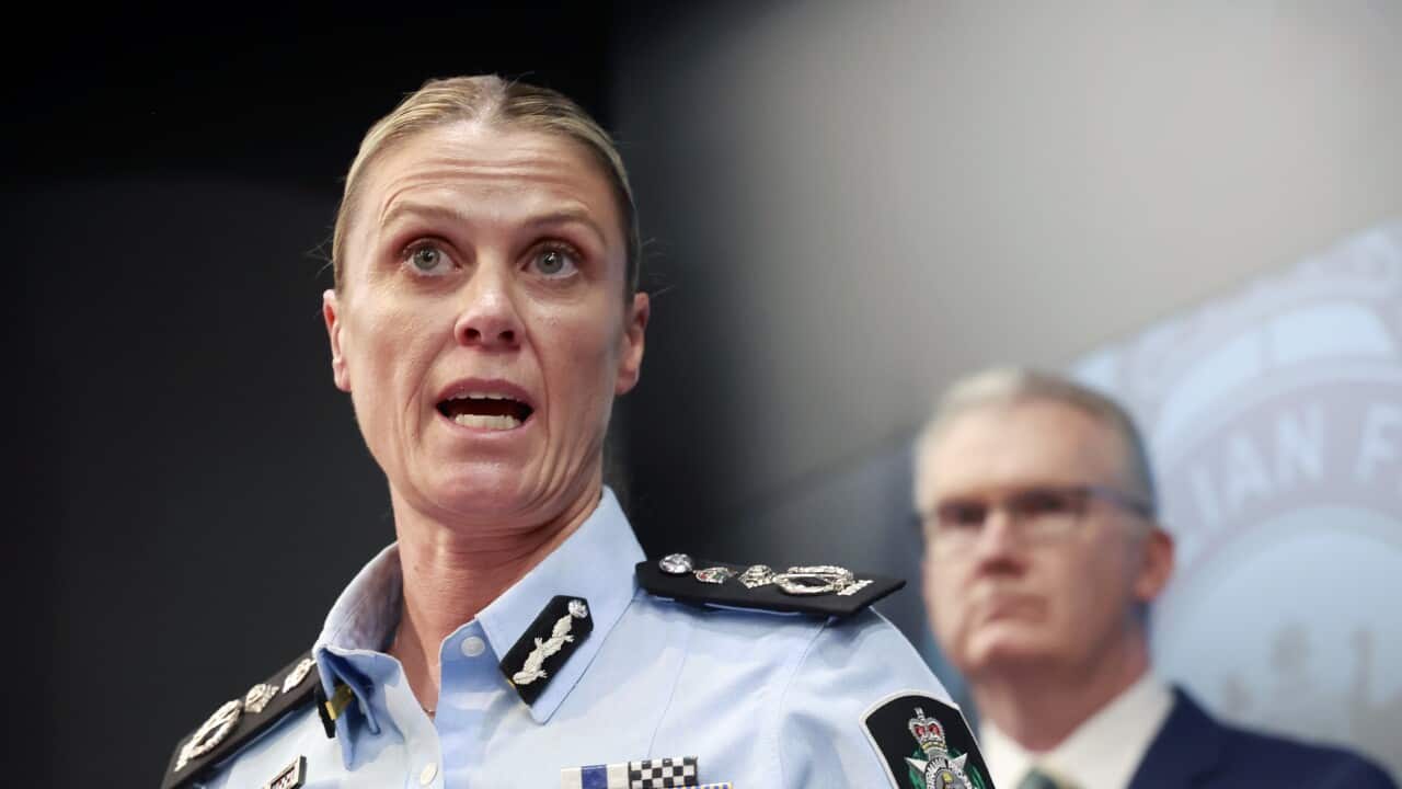 A police officer speaks with a man standing in the background