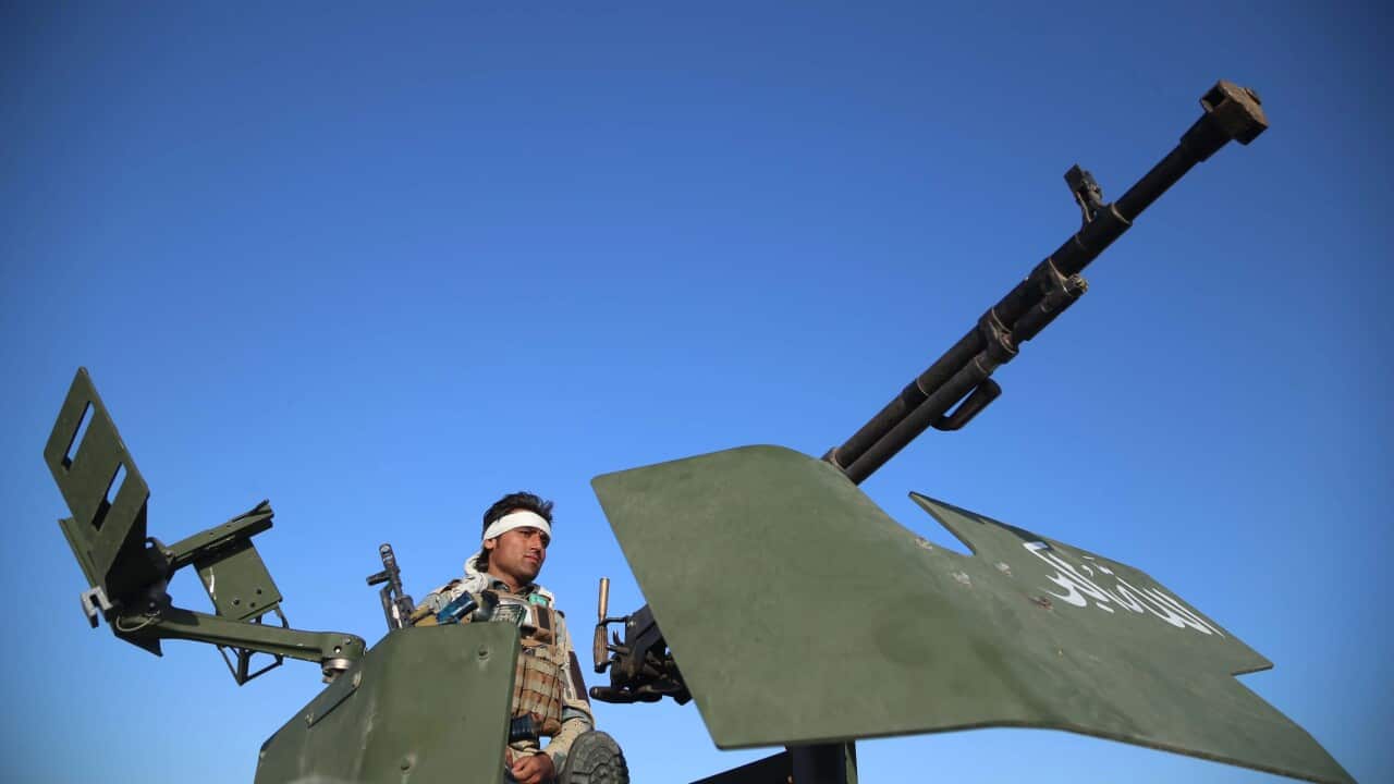 An Afghan security official stands guard as people celebrate Eid in Jalalabad, Afghanistan, 13 May 2021.
