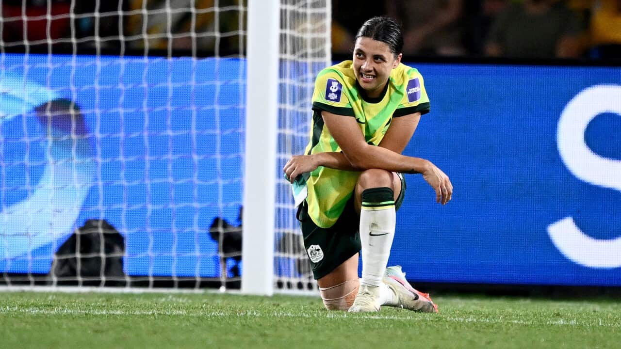A photo of Matildas captain Sam Kerr at the 2026 Women's Asian Cup final. Kerr is dressed in her team kit, on one knee with her arms folded over her leg. She looks exasperated, after another goal has failed to materialise.