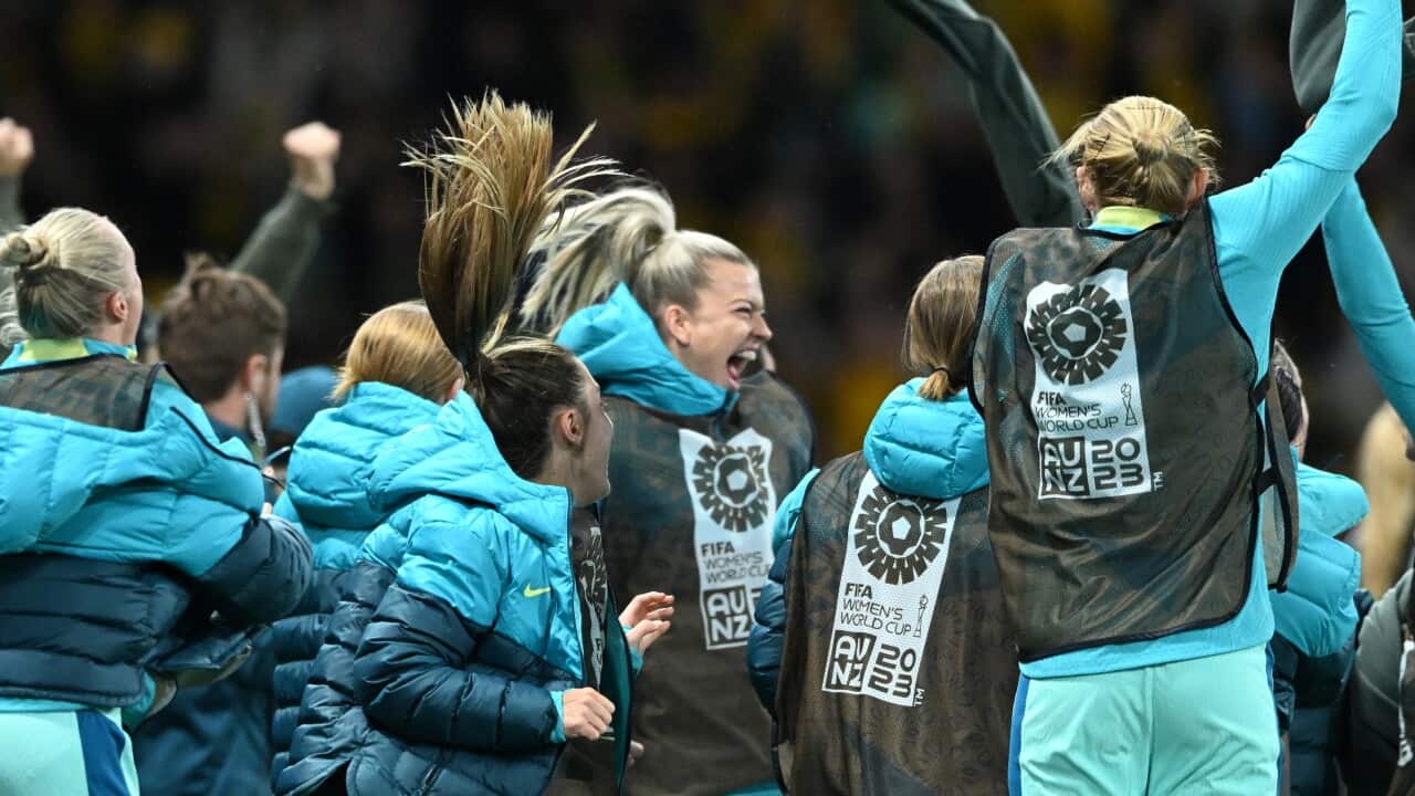 Matildas players cheering on a stadium field.