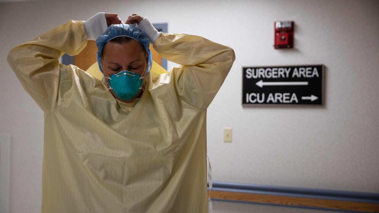 A healthcare professional suits up with PPE to enter a COVID-19 patient's room in the ICU at Van Wert County Hospital in Ohio on 20 November, 2020.