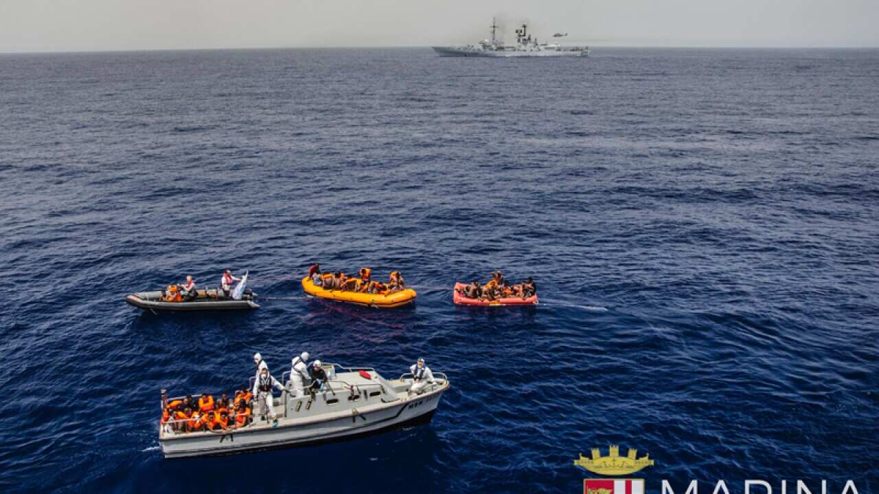 Rescuers tow migrants to board the Italian Navy ship Vega