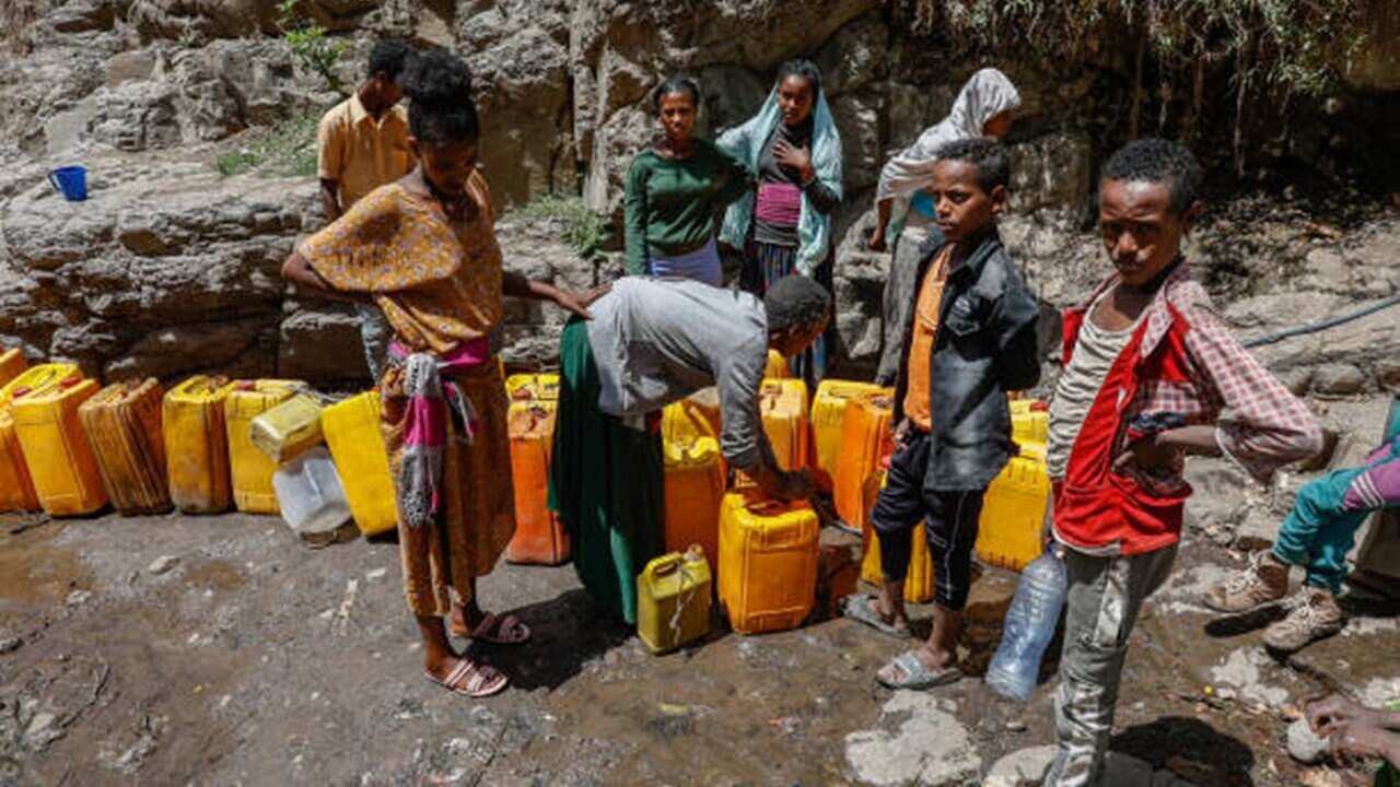 Women and young boys line up in a river bed to fetch water from a small stream of water running through the city of Lalibela.jpg