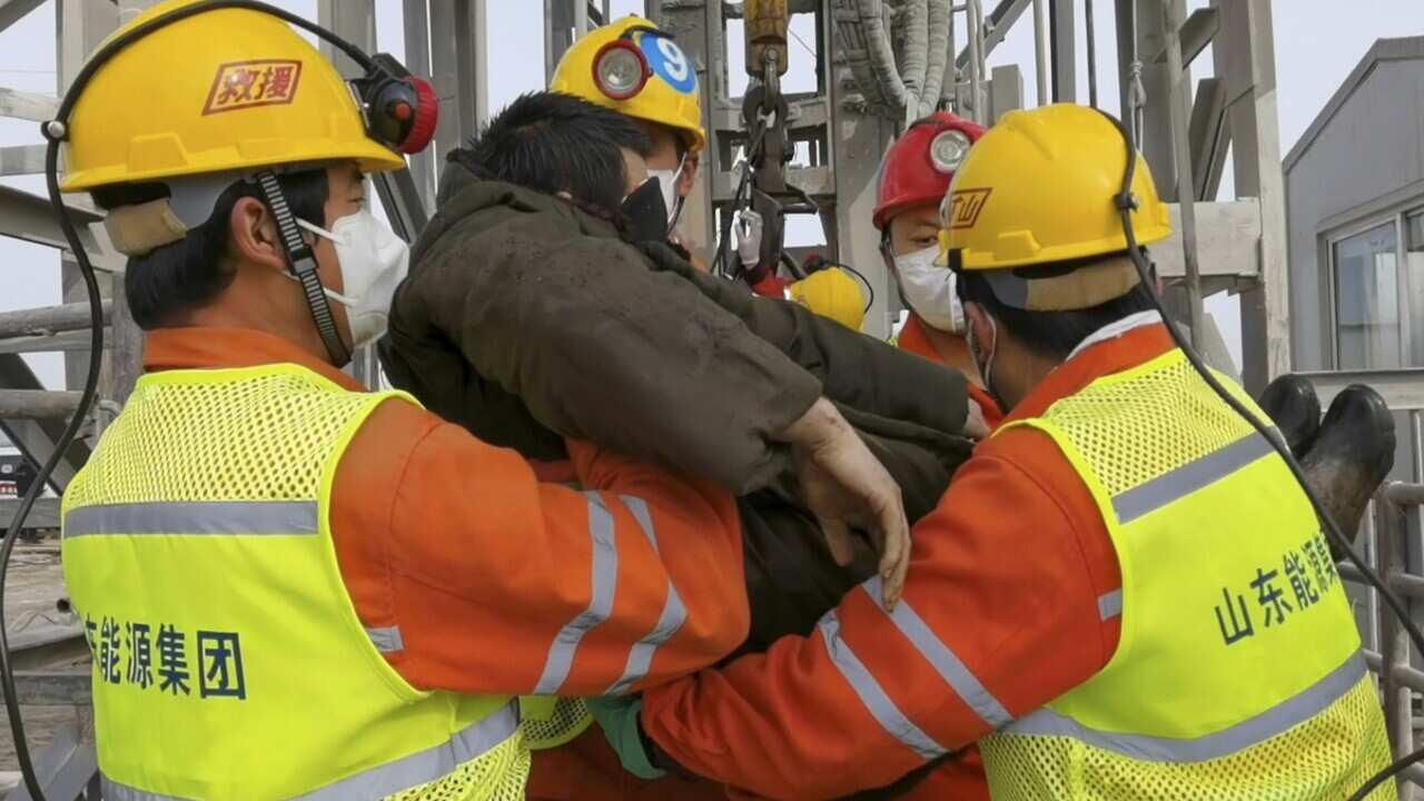 In this photo released by Xinhua News Agency, rescuers carry a trapped miner from the mine in Qixia City on Sunday.