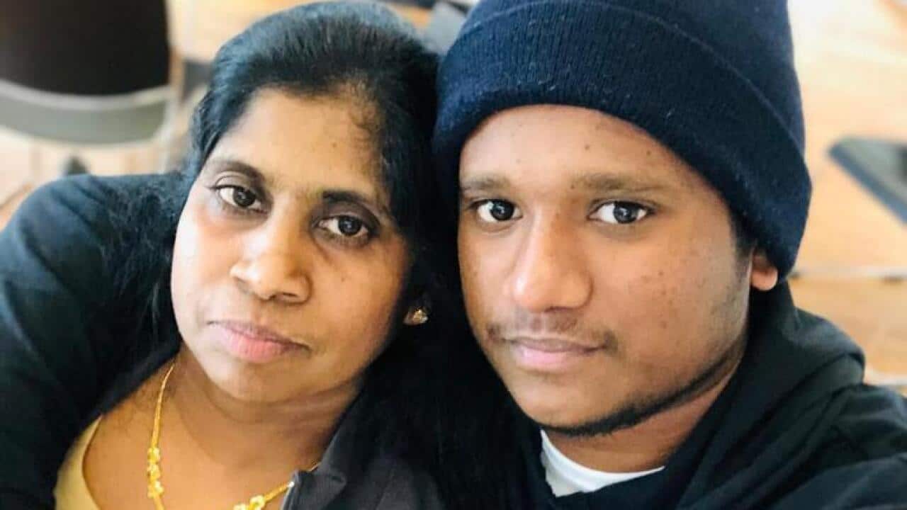 A son drapes his arm around his mother's shoulders.