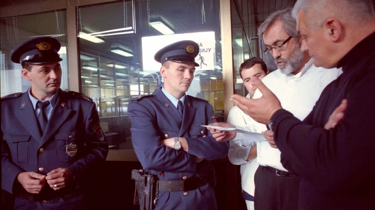 Belgrade's daily newspaper "Dnevni Telegraf" editor in chief Slavko Curuvija,center,and the paper's columnist Sasa Tijanic talk to Serbian police officers in Belgrade Wednesday October 14 1998 as the paper was shut down. Serbian government decided to shu