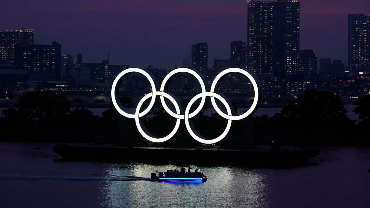 The Olympic rings float in the water at sunset in Tokyo.
