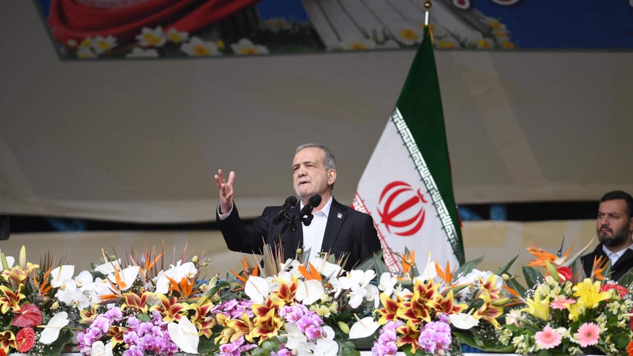 Iranian president Masoud Pezeshkian in front of a state flag and flowers