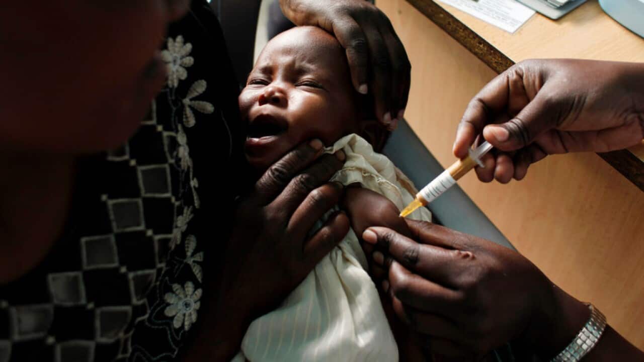 A mother holds her baby as she receives a new malaria vaccine.