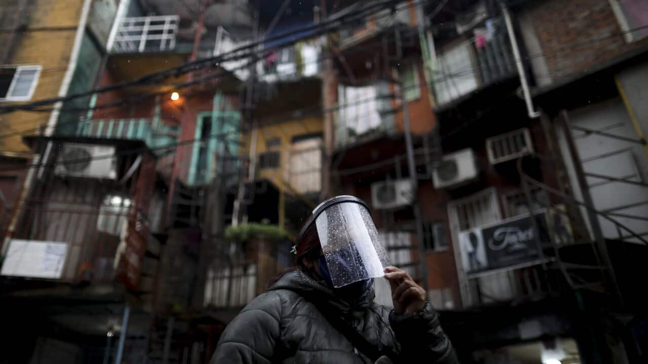 A woman wearing a face shield walks through the Villa 31 neighbourhood