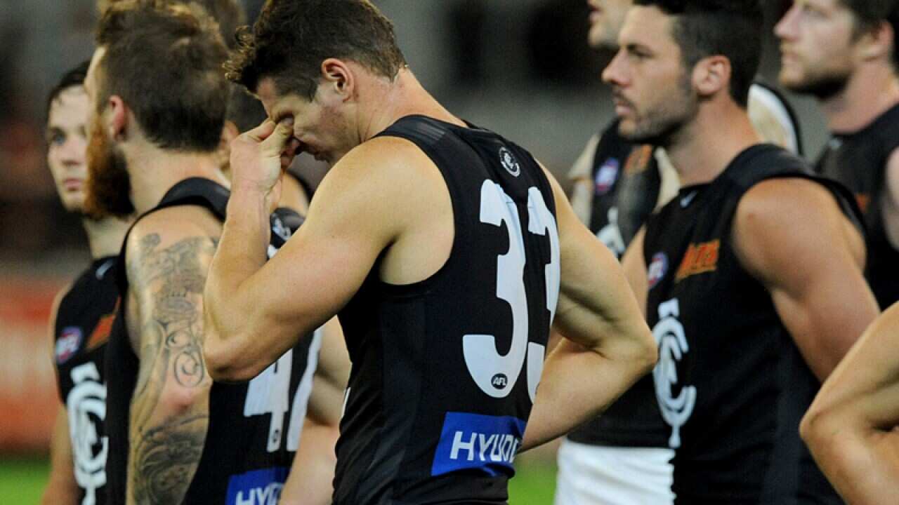 Dejected Carlton players walk off the ground