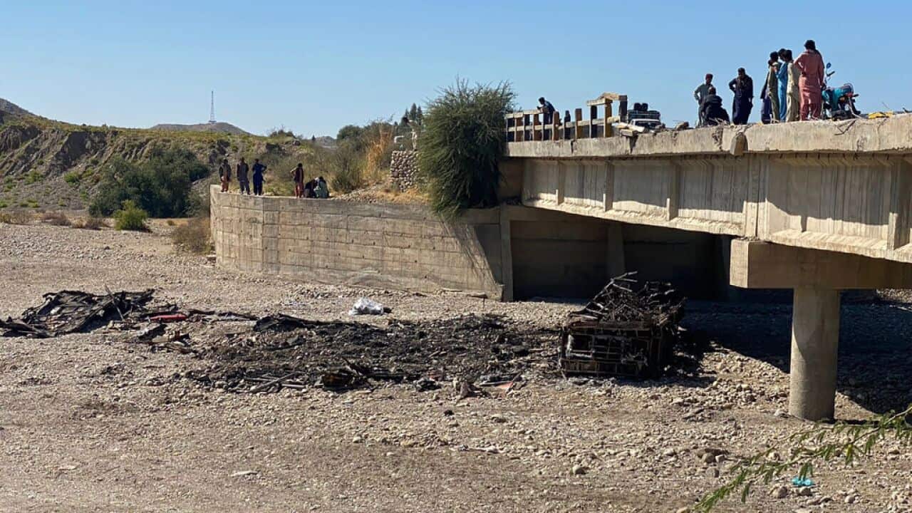 Residents gather over a bridge to watch the wreckage of a burnt passenger bus in Lasbela district of Pakistan's Balochistan province.
