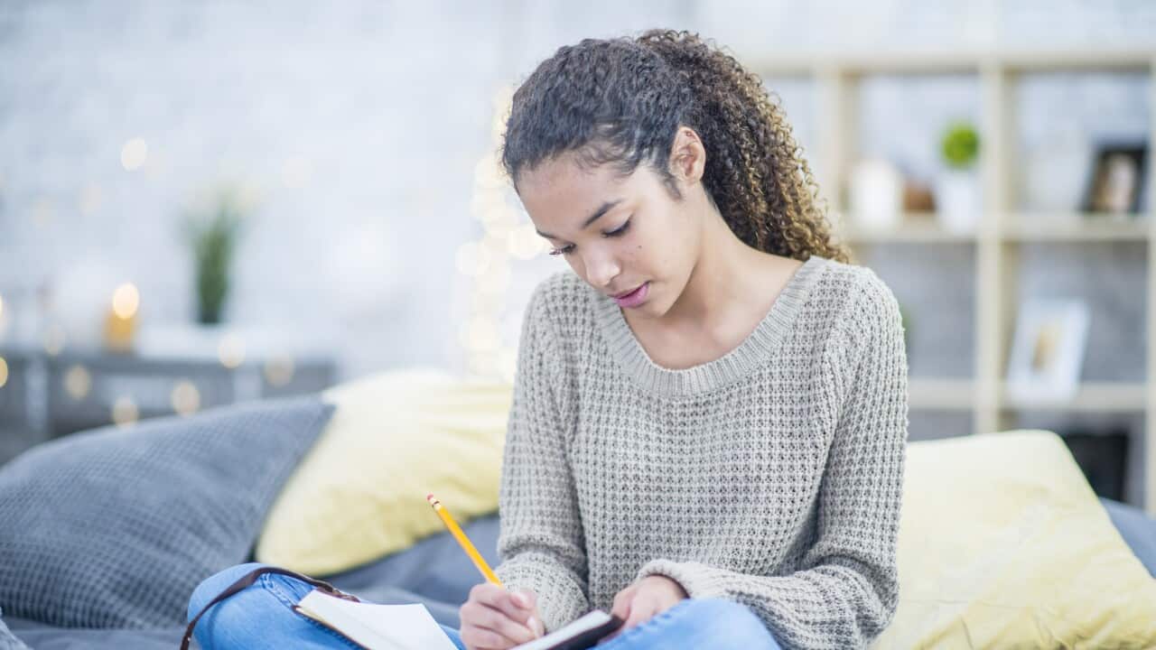 Teen girl journaling on her bed