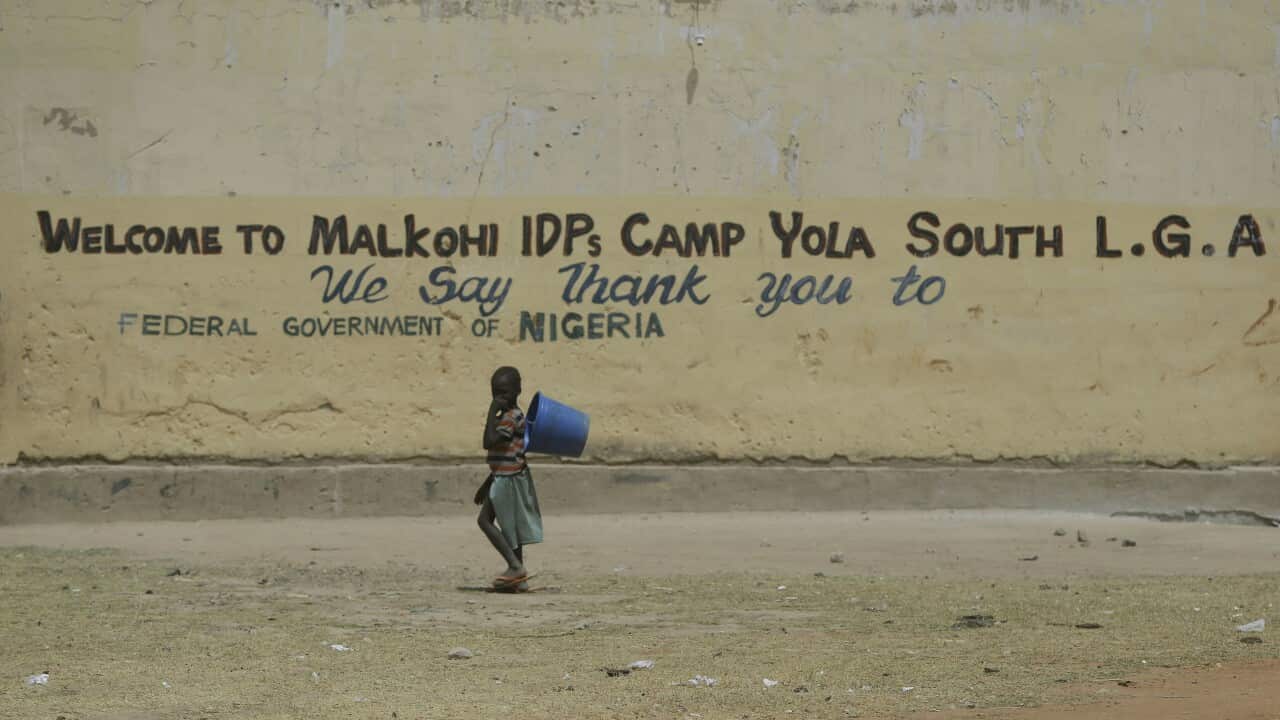 A Child displaced by Islamist extremist walk past a welcome sign to Malkohi camp in Yola, Nigeria.