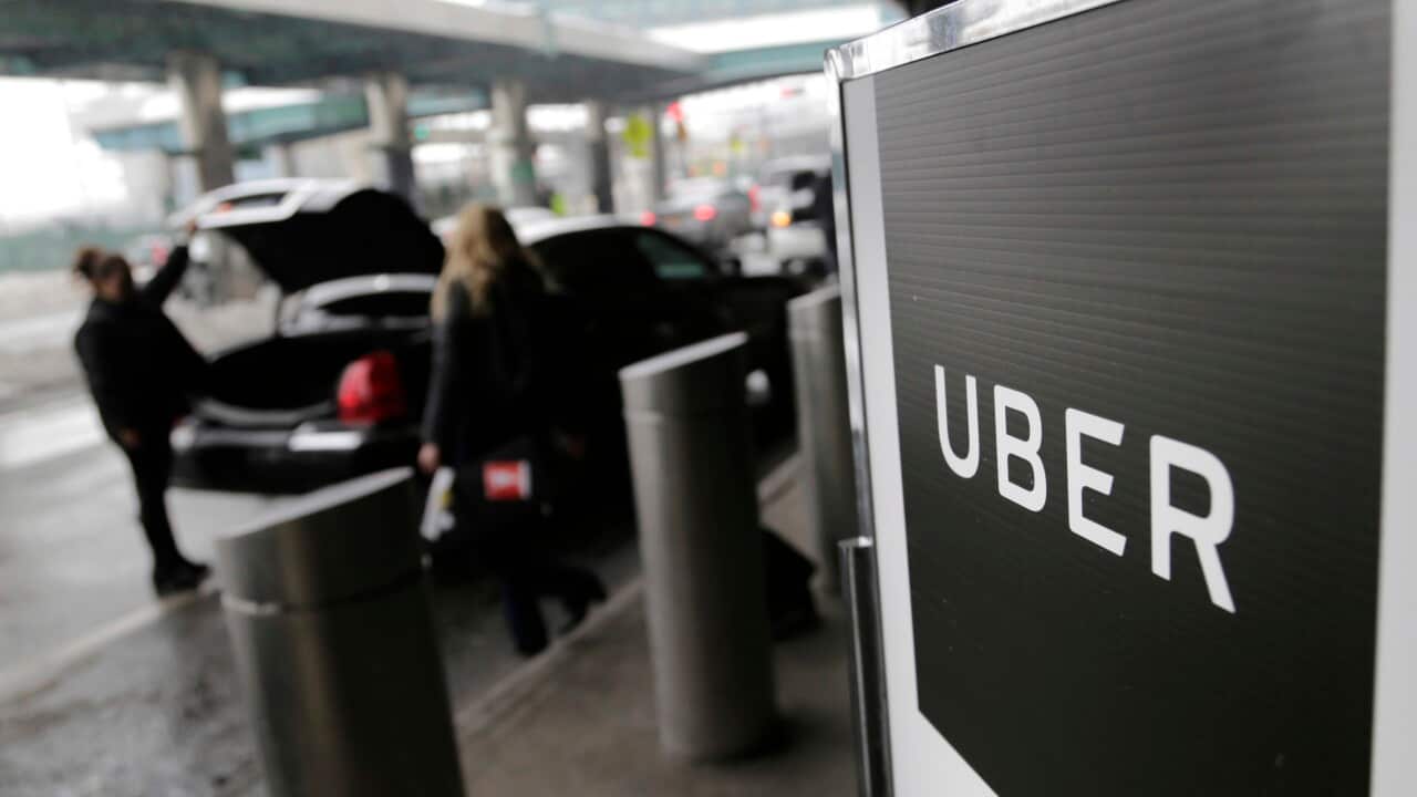 Two people getting into a car parked near a sign that reads: “UBER“.