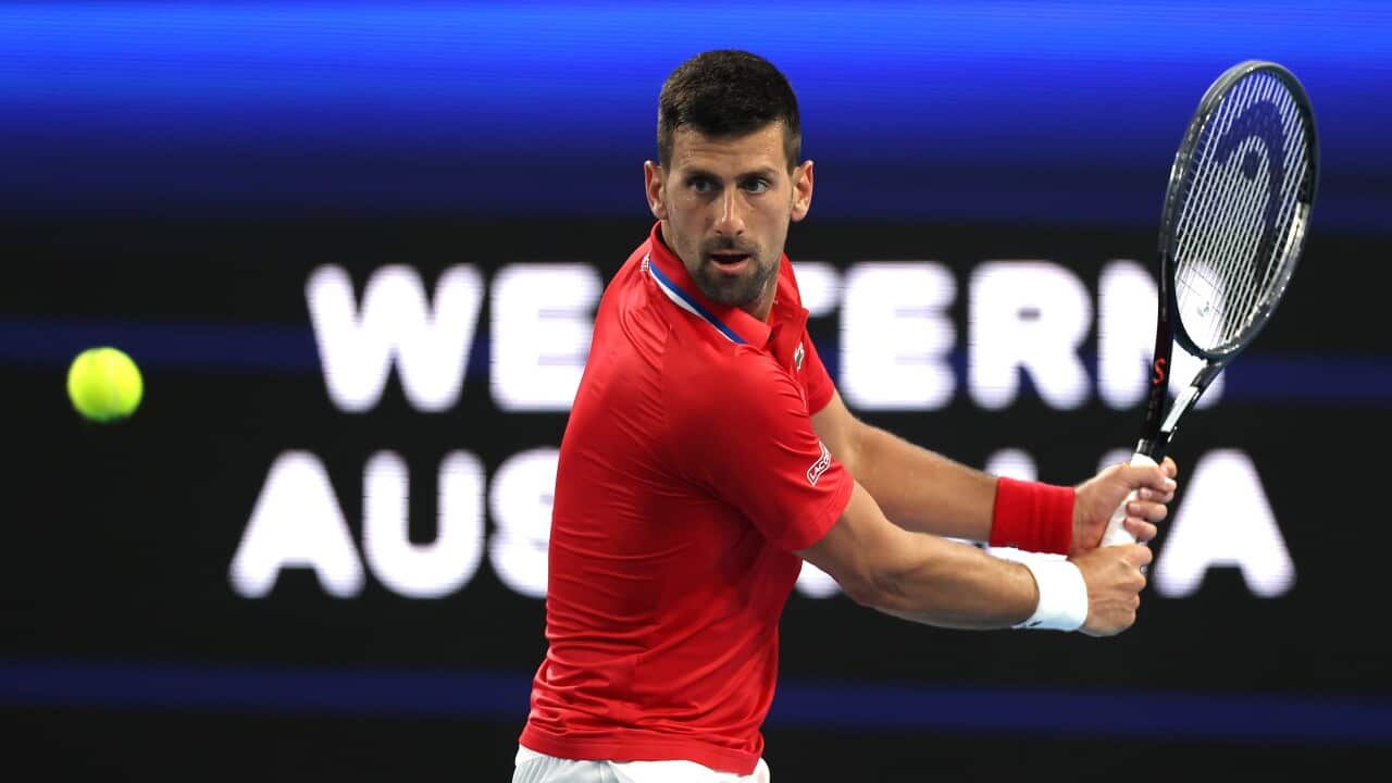 Novak Djokovic taking a swing at a tennis ball with his racquet