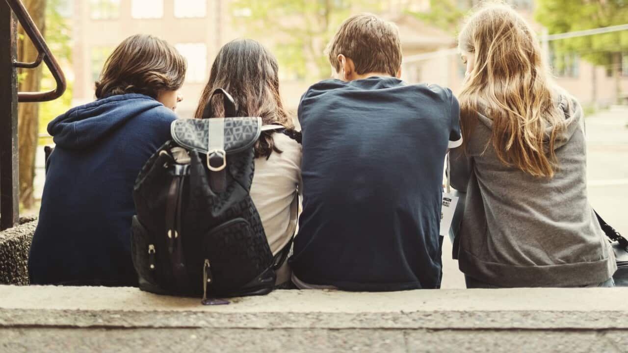 Rear view of teenagers sitting on steps outdoors