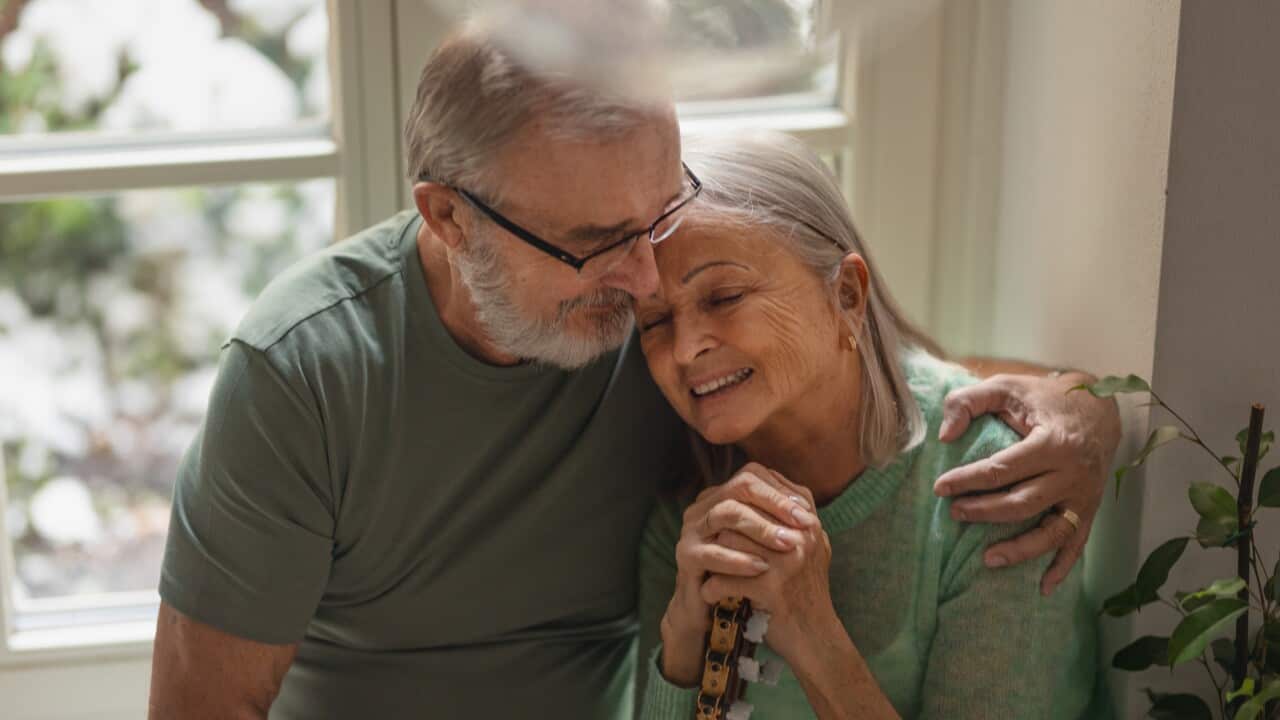 Portrait of senior husband embracing his wife at home.