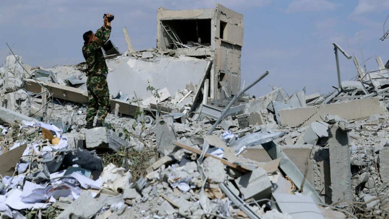 A Syrian soldier films the damage of the Syrian Scientific Research Center which was damaged by US-led air strikes.