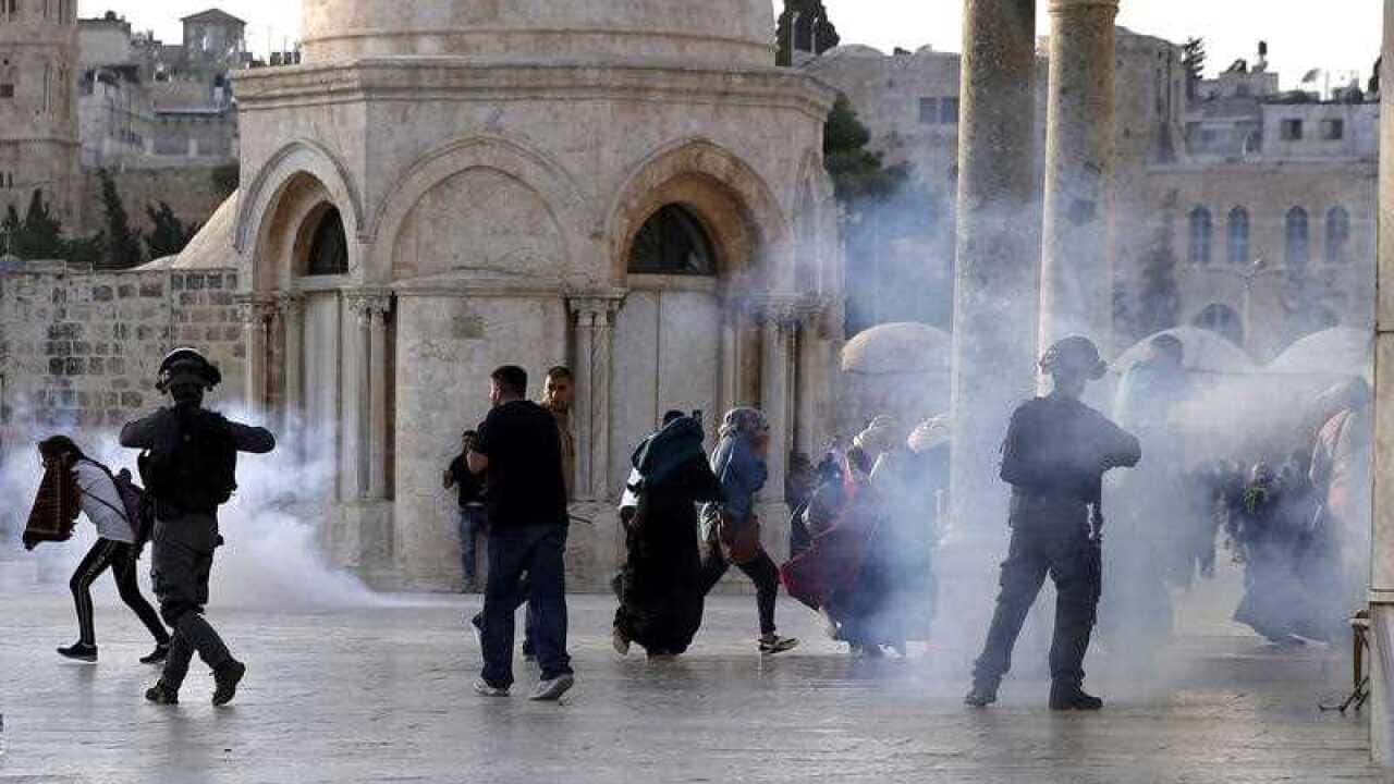 Israeli border police officers throw tear gas towards Palestinians next to the Dome of the Rock Mosque in the Al Aqsa Mosque compound