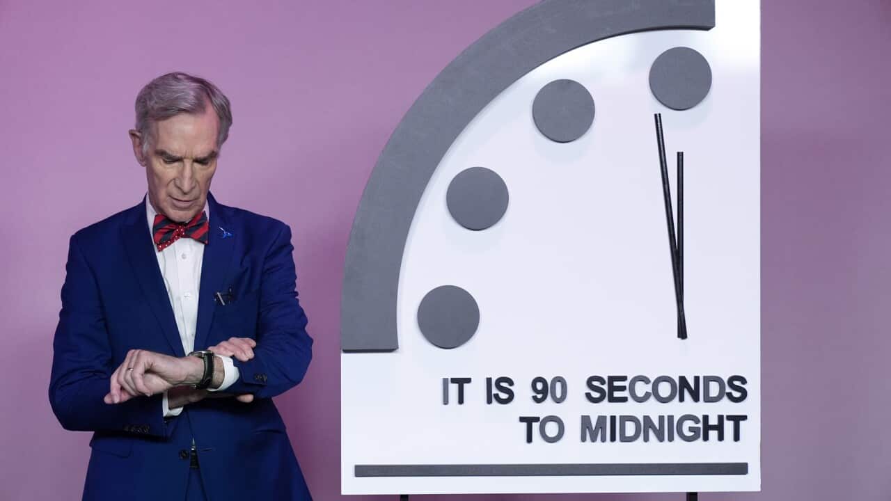 Science educator Bill Nye looks at his watch next to the Doomsday Clock.
