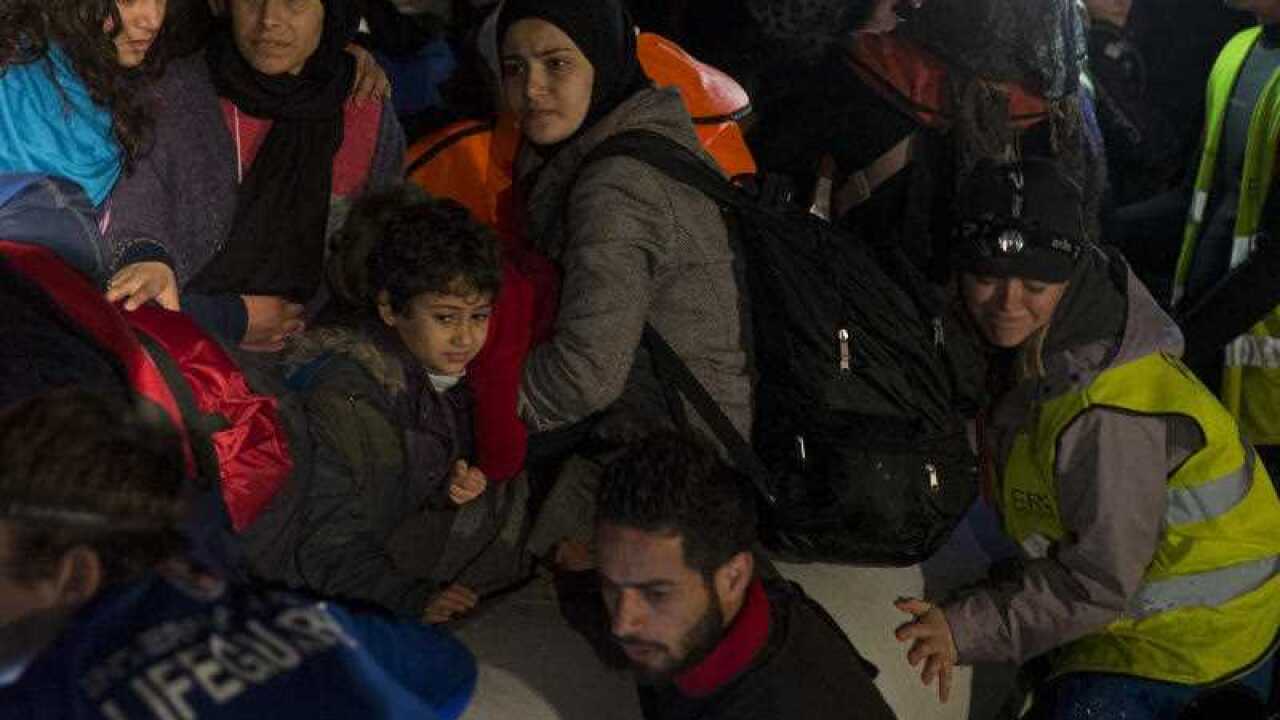 Volunteers try to push an overcrowded boat with dozens of migrants and refugees from nearby Turkey as they arrive on Greek island of Lesbos.