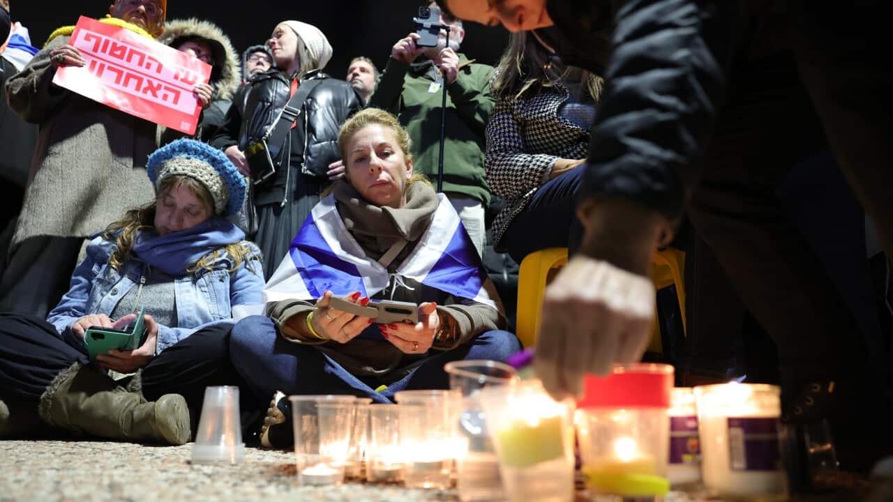 People gather to light candles at a vigil.