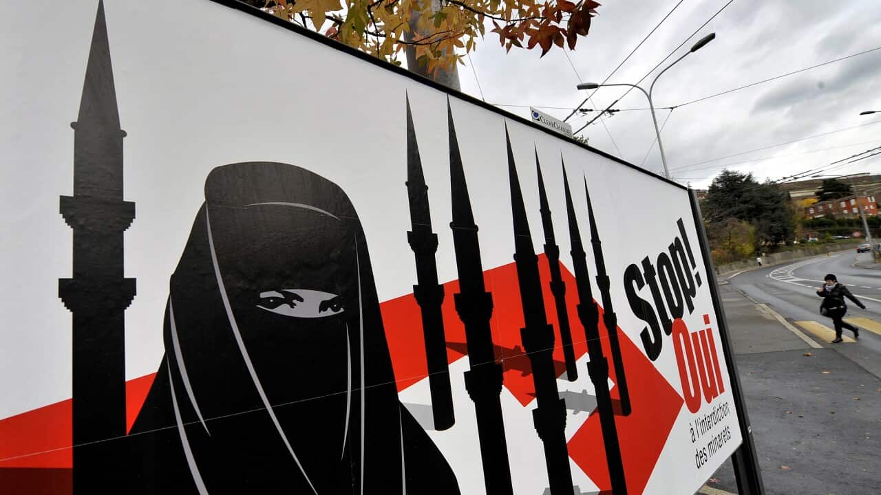 A woman walks behind a campaign posters