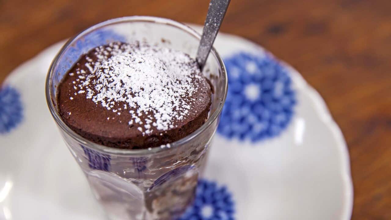 A chocolate cake in a glass sits on a vibrant white and blue plate.
