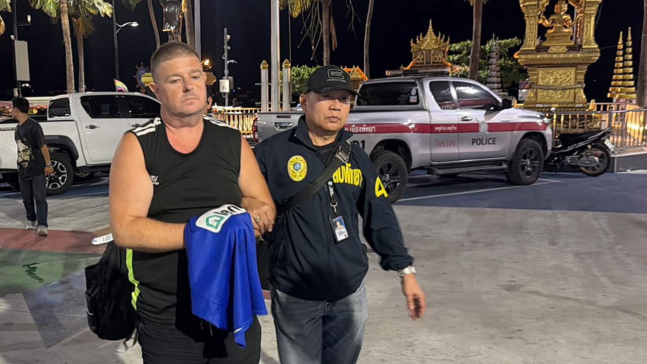 A man is walked through a street in Thailand a police officer.