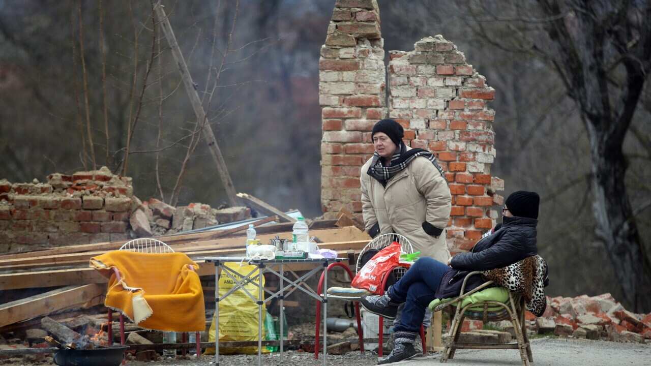 Two women gather in front of a destroyed home in Petrinja, Croatia