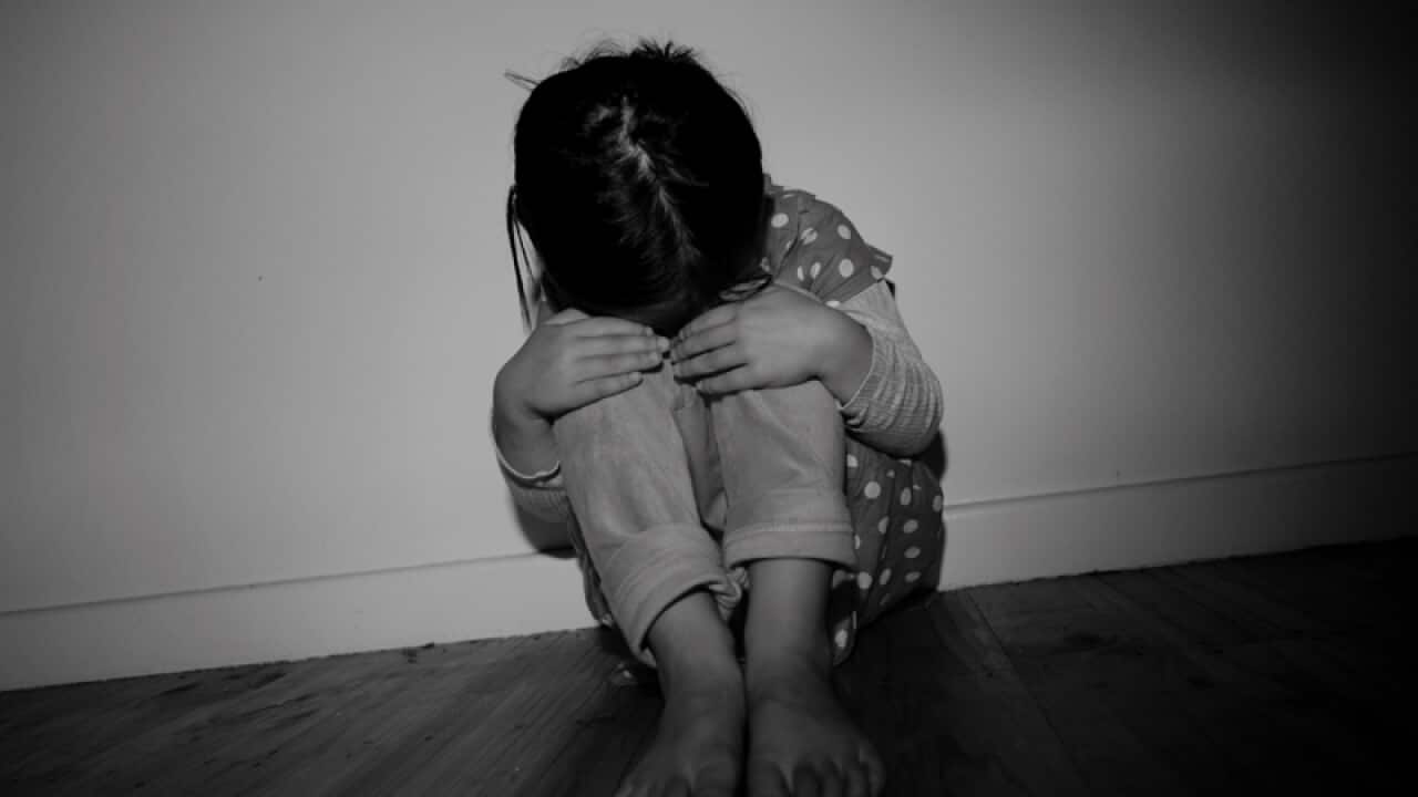 A child poses for a photograph to illustrate child abuse
